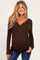 woman wearing a brown long sleeve maternity top with a v-neckline and a visible baby bump