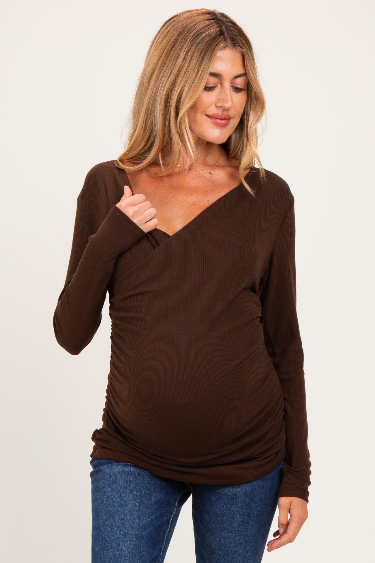 woman wearing a dark brown maternity wrap top with long sleeves and a visible baby bump