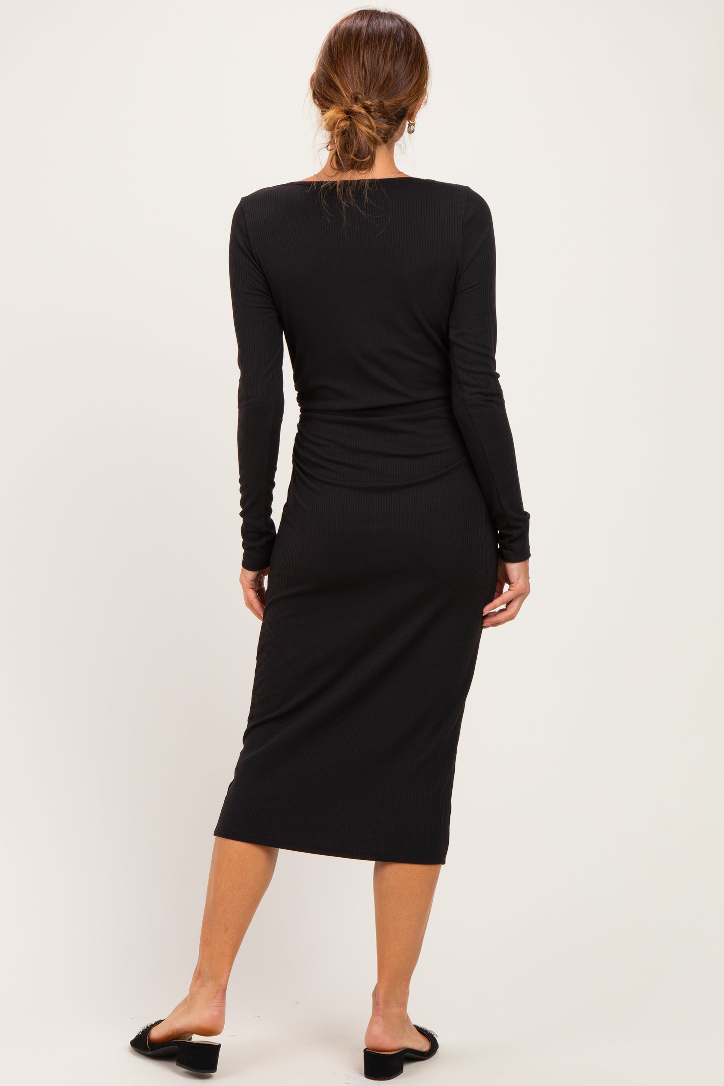 woman wearing a black ribbed long sleeve midi dress, view shows the back and wrist detail, paired with black sandals