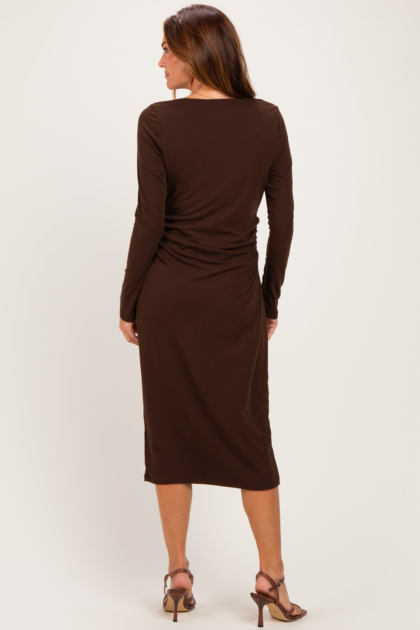 woman wearing a dark brown long sleeve dress with a fitted silhouette and ruched detailing on the back