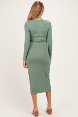 woman wearing a green ribbed maternity dress with long sleeves and a fitted silhouette, showing her baby bump from the back