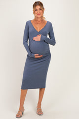 woman wearing a blue ribbed maternity dress with a fitted silhouette and v-neck, holding her baby bump