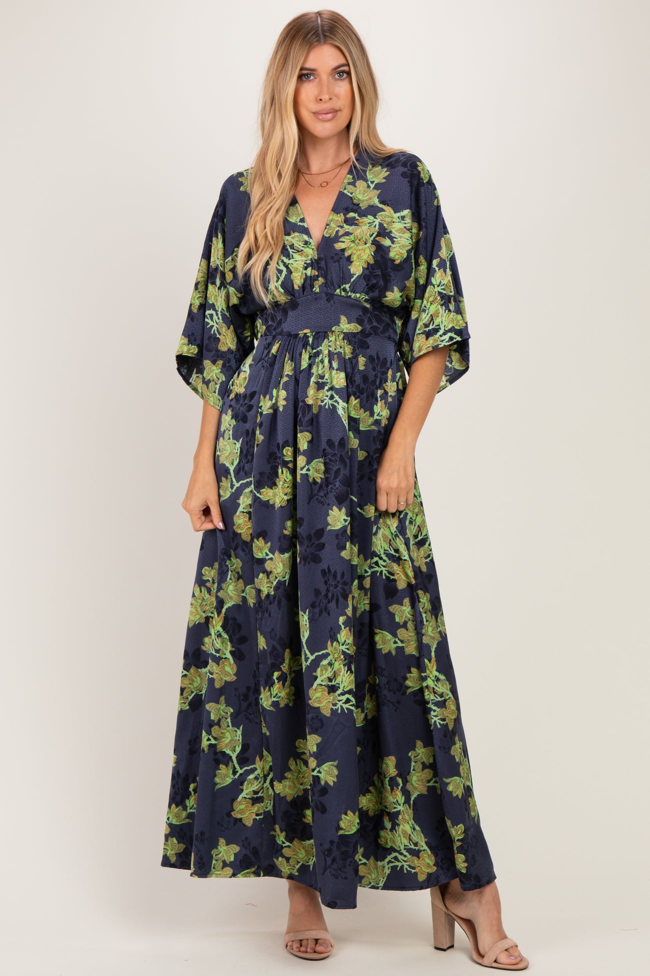 woman wearing a navy blue maxi dress with floral print and kimono sleeves, styled with heels