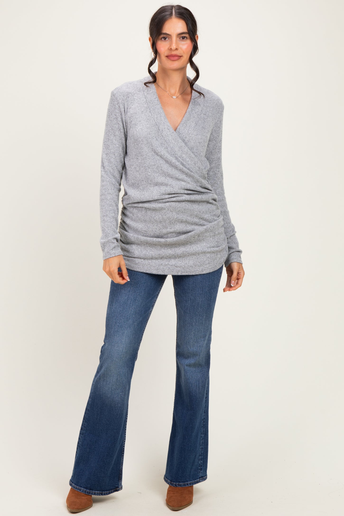 woman wearing a grey wrap sweater and flared denim jeans with brown ankle boots
