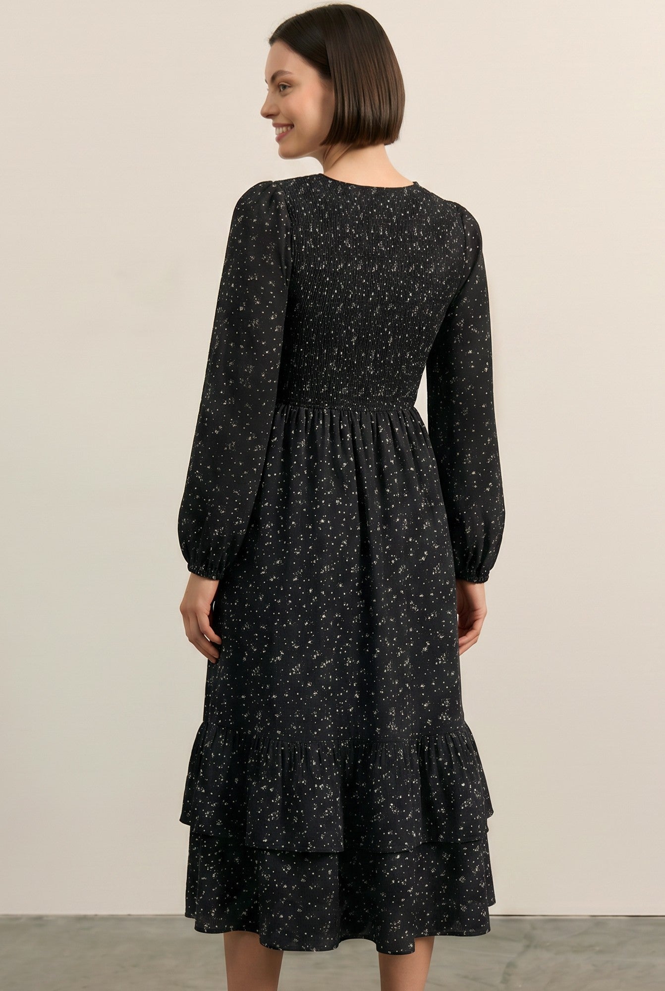 woman wearing a black long sleeve floral print midi dress with a smocked bodice and tiered ruffle hem