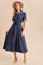 woman wearing a navy blue short sleeve button-up dress with floral print and a tie waist, paired with a beige hat