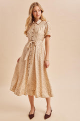 woman wearing a cream button-up midi dress with floral print and a tied waist, paired with brown heeled shoes