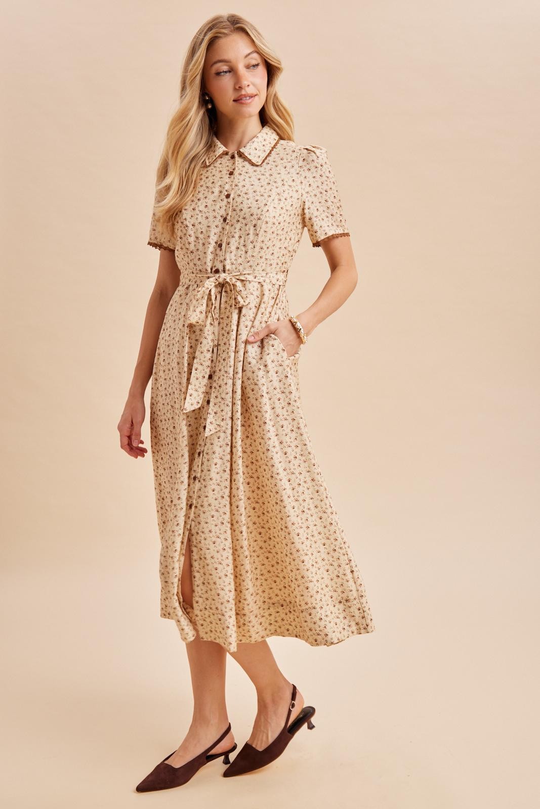 woman wearing a beige midi dress with short sleeves, a collar, and a tie waist detail