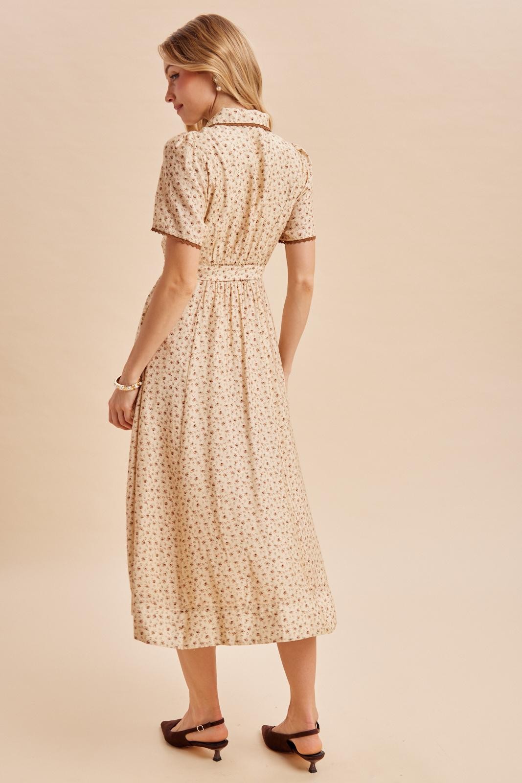 woman wearing a beige midi dress with floral print and short sleeves, seen from the back
