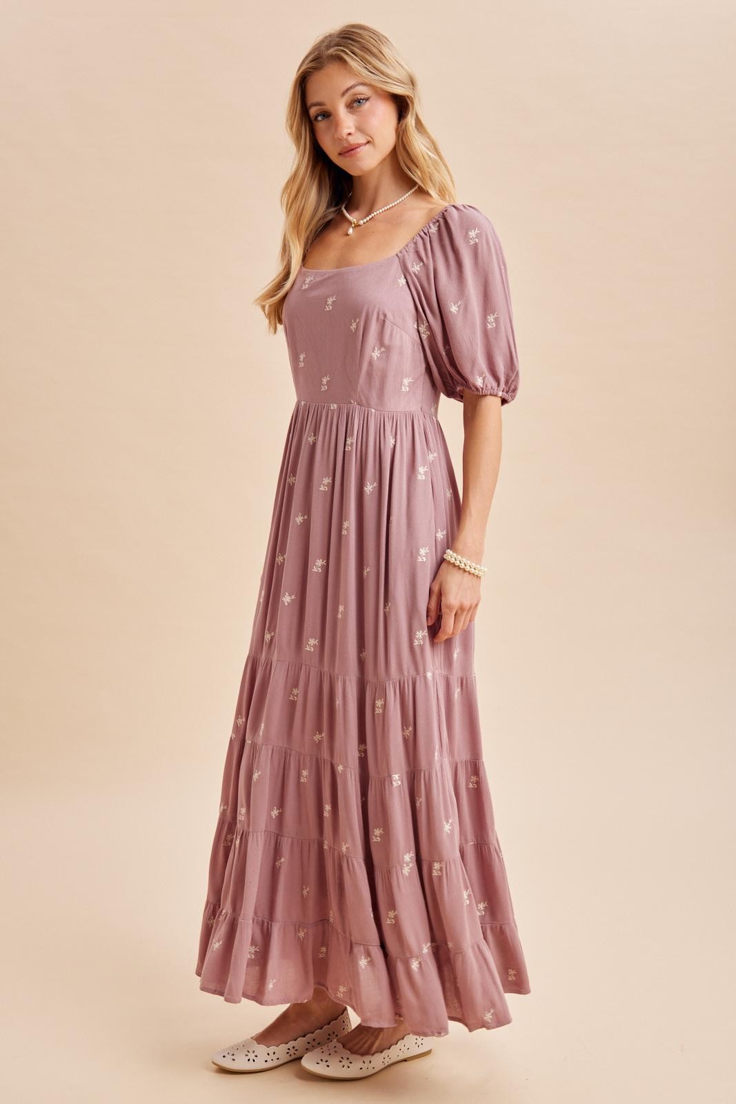 woman wearing a mauve maxi dress with puff sleeves and floral embroidery