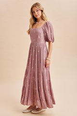 woman wearing a mauve maxi dress with puff sleeves and floral embroidery