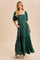 woman wearing a green maxi dress with puff sleeves and floral embroidery, styled with pockets and a flowing silhouette