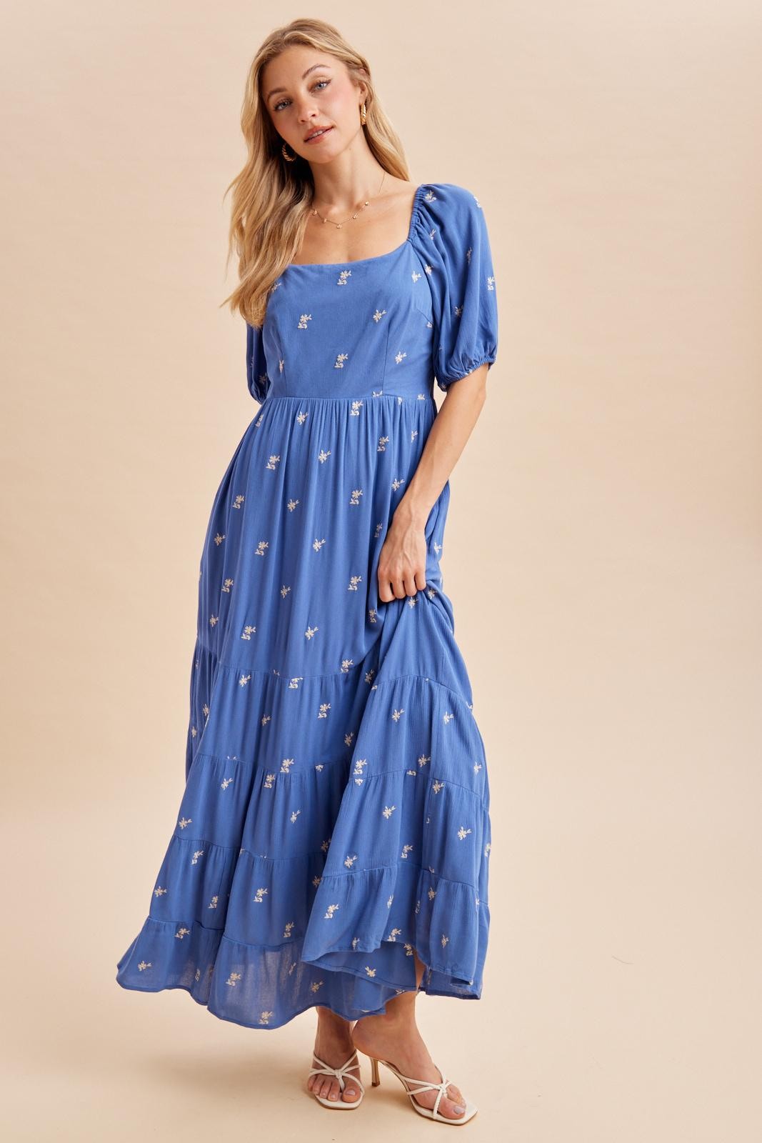 woman wearing a blue maxi dress with puff sleeves and floral embroidery