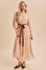 woman wearing a floral printed long sleeve maxi dress with a tied waist belt and pointed toe heels