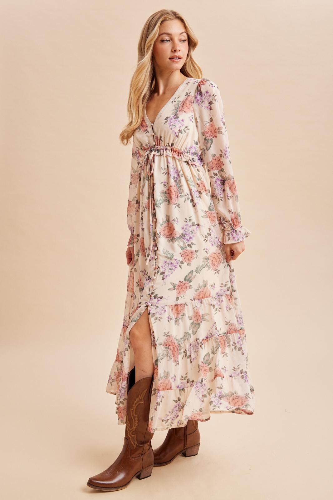 woman wearing a floral maxi dress with a deep v-neck and long sleeves, paired with brown cowboy boots