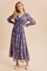 woman wearing a purple floral maxi dress with long sleeves and a tie waist detail
