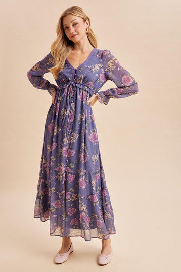 woman wearing a purple floral maxi dress with long sleeves and a tie waist detail