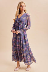 woman wearing a flowy purple floral maxi dress with long sleeves and a cinched waist, paired with pink flats