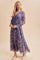woman wearing a flowy purple floral maxi dress with long sleeves and a cinched waist, paired with pink flats