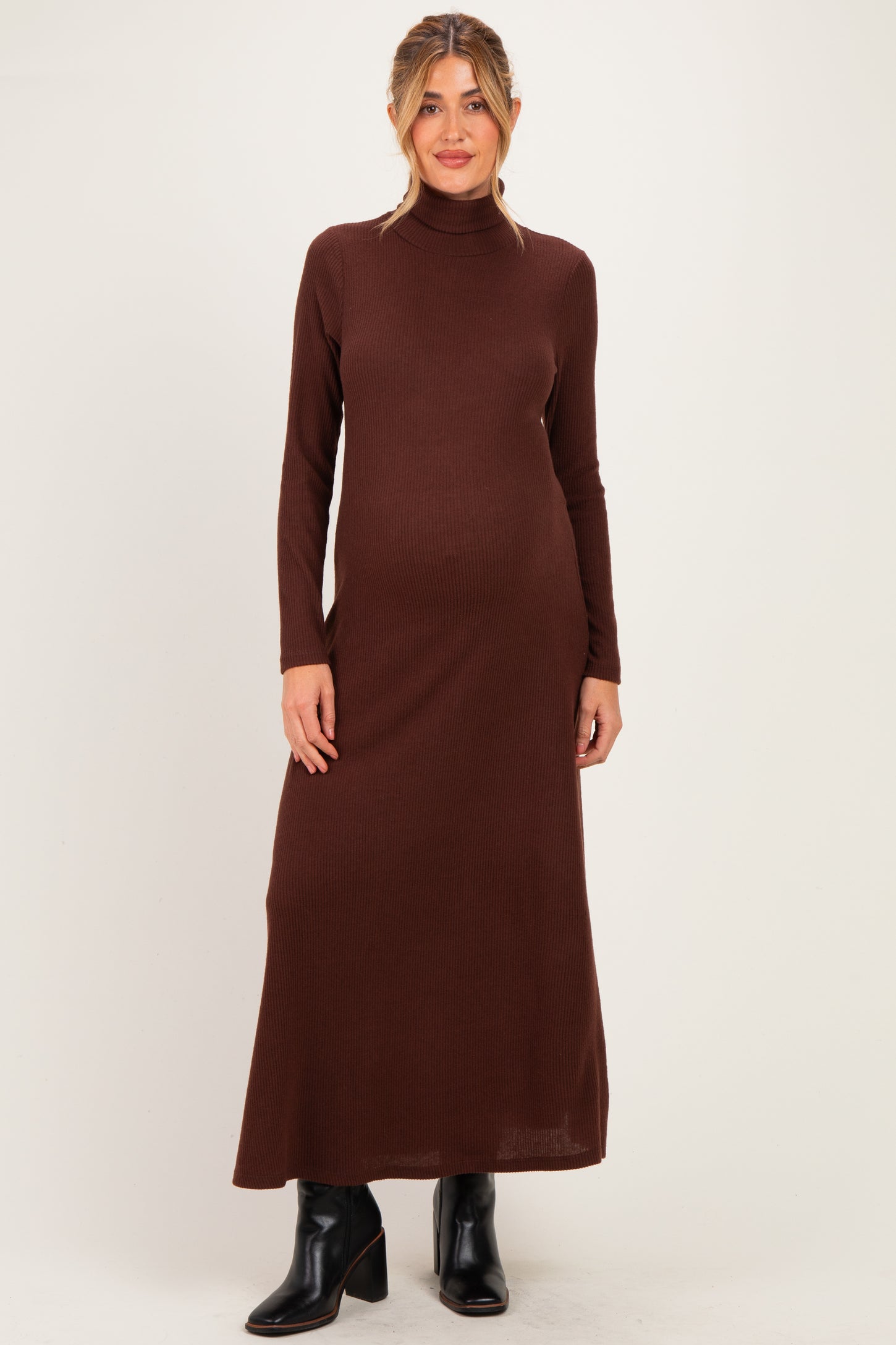 woman wearing a brown ribbed turtleneck maternity dress with long sleeves and a flowing silhouette