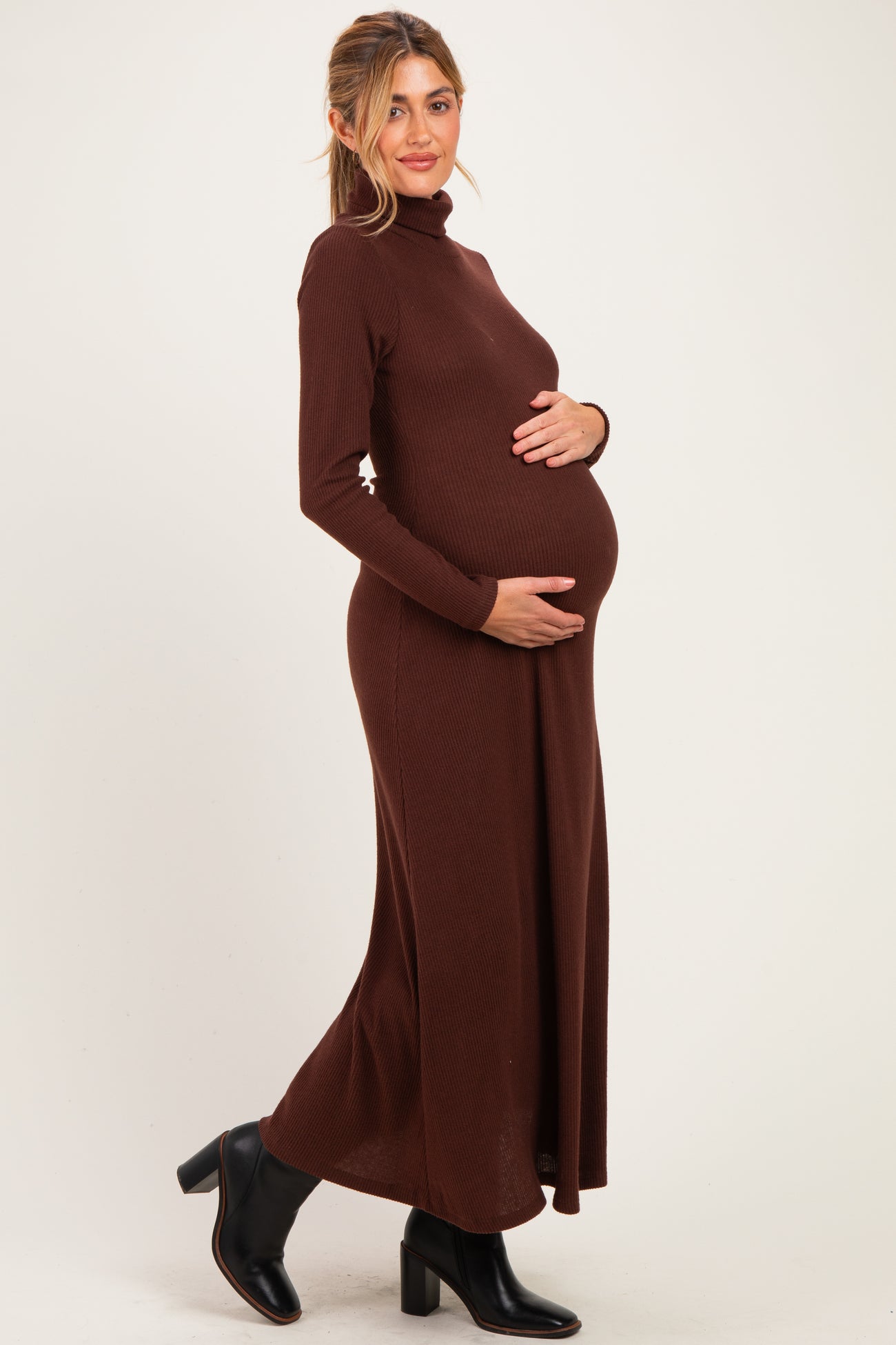 woman wearing a brown long sleeve ribbed maternity dress and holding her baby bump