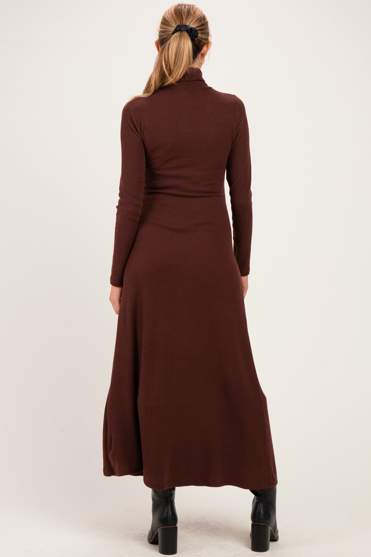 woman wearing a brown long sleeve ribbed maternity dress with a flowing skirt, showing her baby bump from the back