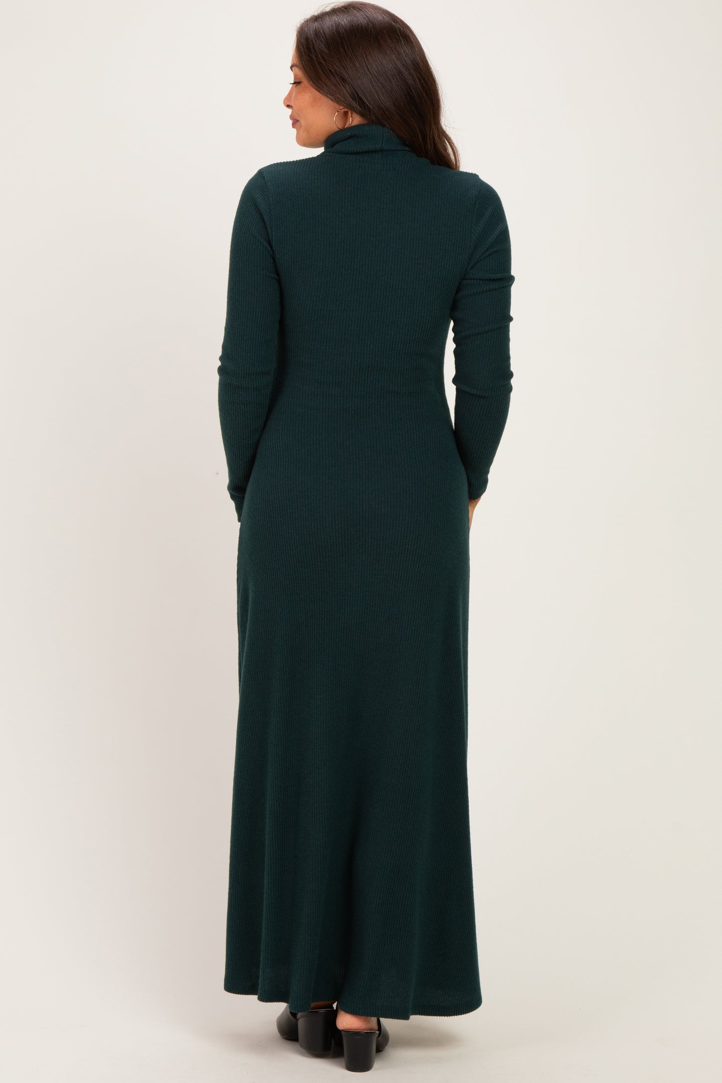 woman wearing a dark green maternity maxi dress with a high neck and long sleeves, showing the back view