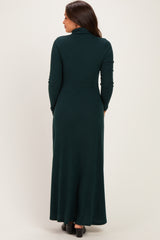 woman wearing a dark green maternity maxi dress with a high neck and long sleeves, showing the back view