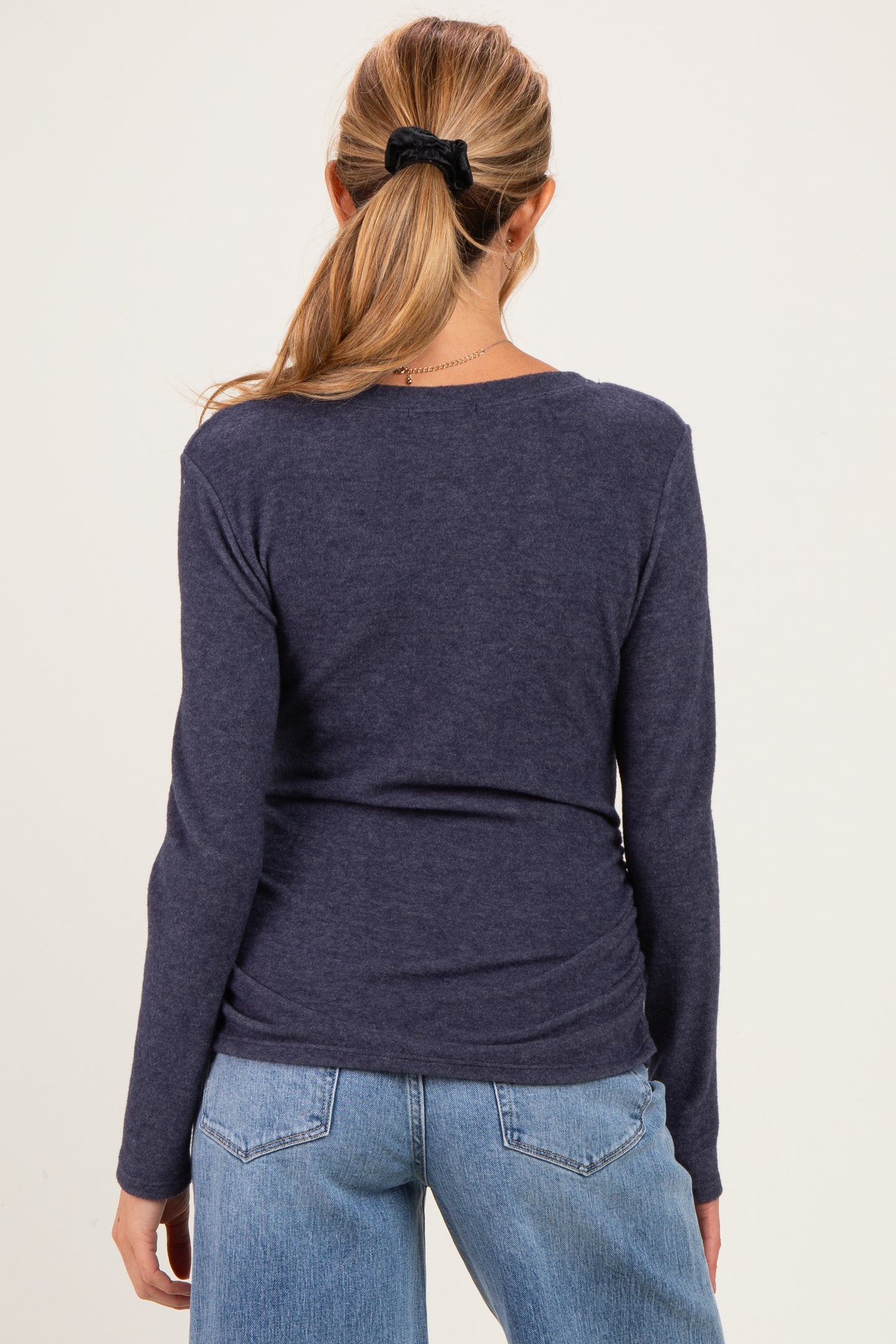 woman wearing a navy long sleeve maternity top, viewed from the back, with fitted styling and soft fabric
