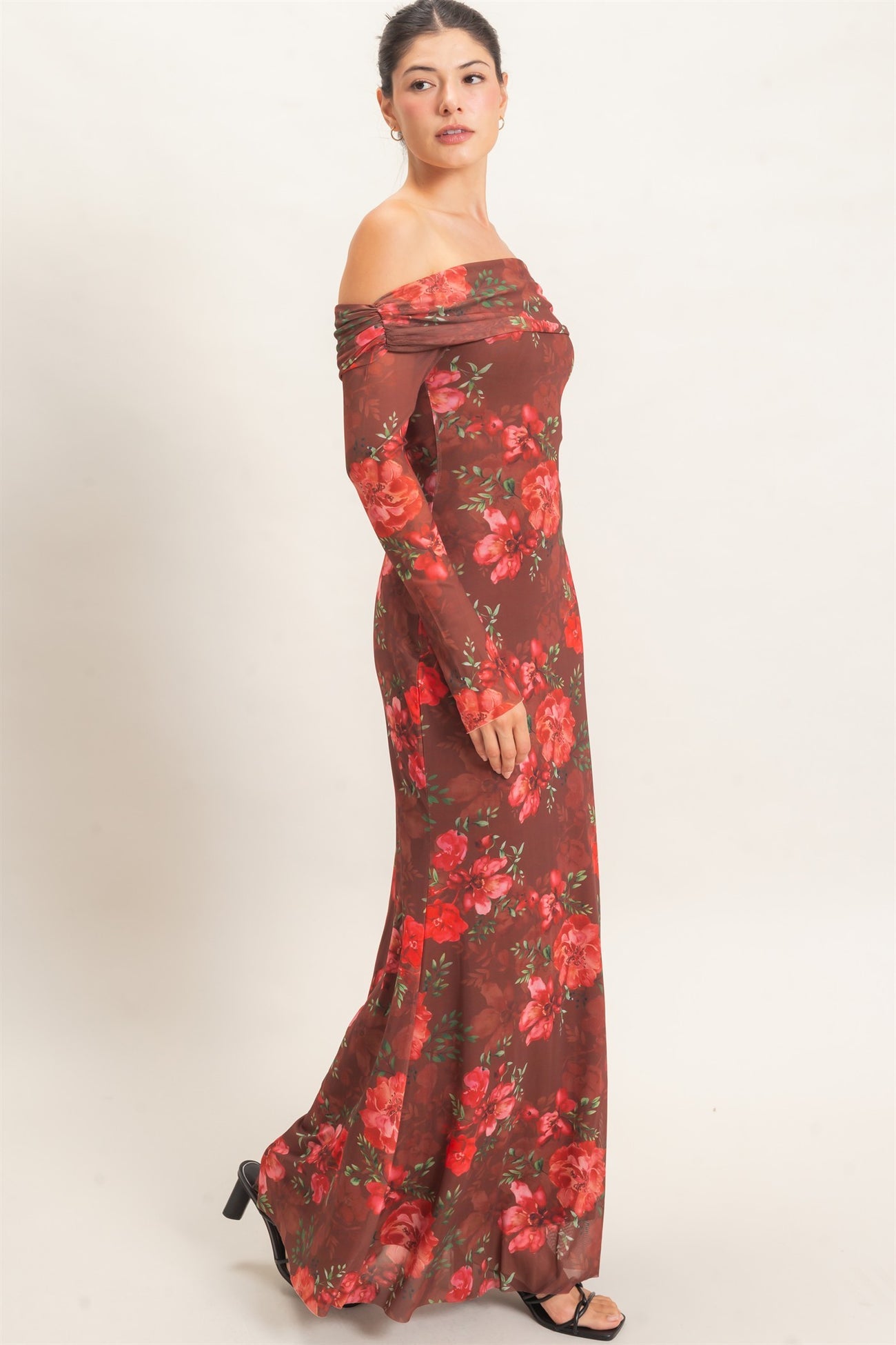 woman wearing a long off-the-shoulder floral maxi dress in shades of brown and red with a fitted silhouette