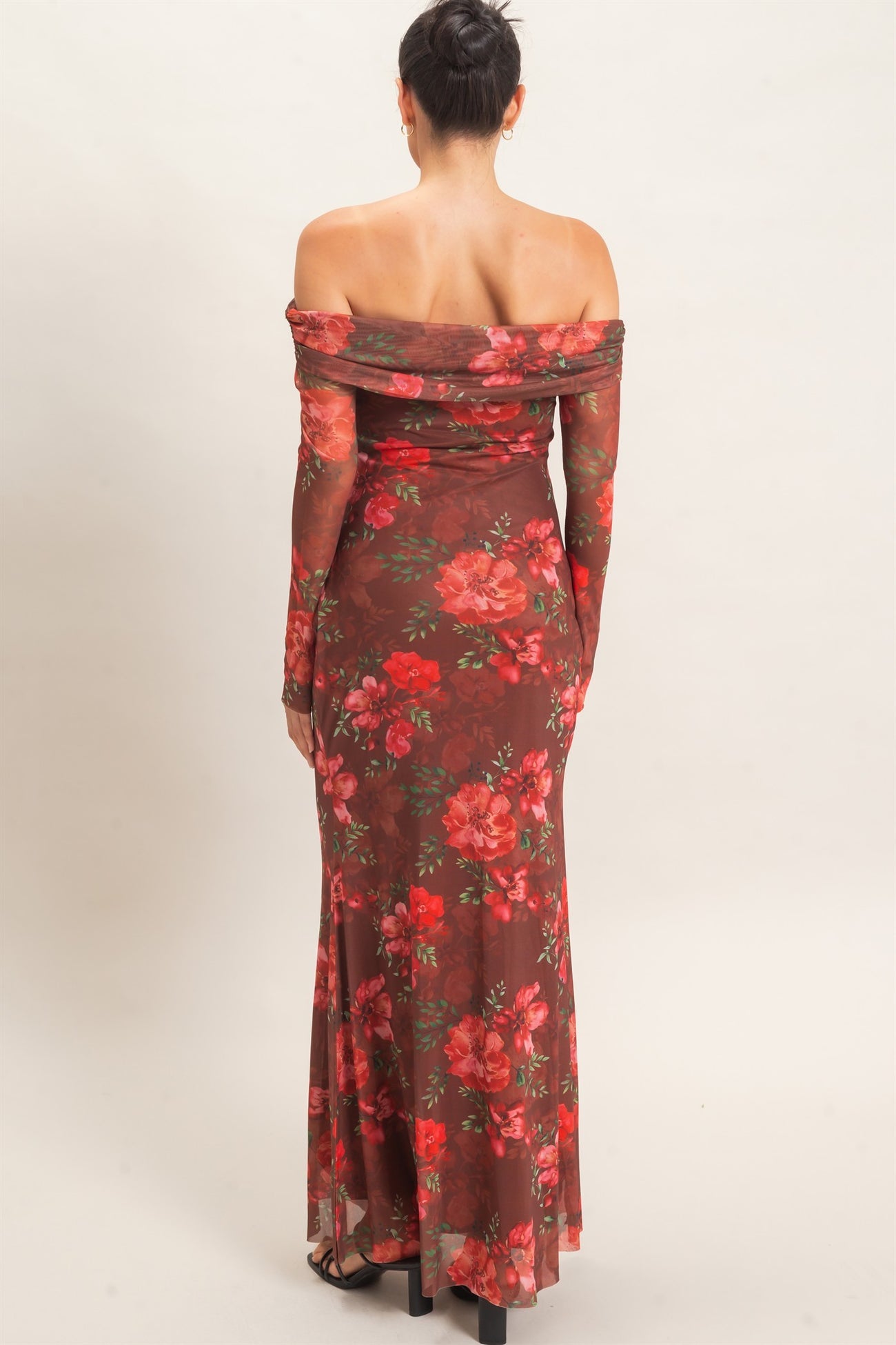 woman wearing a floral off-the-shoulder brown maxi dress with long sleeves and a fitted silhouette