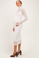 woman wearing a white maternity dress with a textured overlay and long sleeves, showing her baby bump