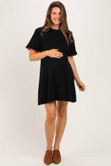woman wearing a black maternity dress with short sleeves and a relaxed fit, holding her baby bump