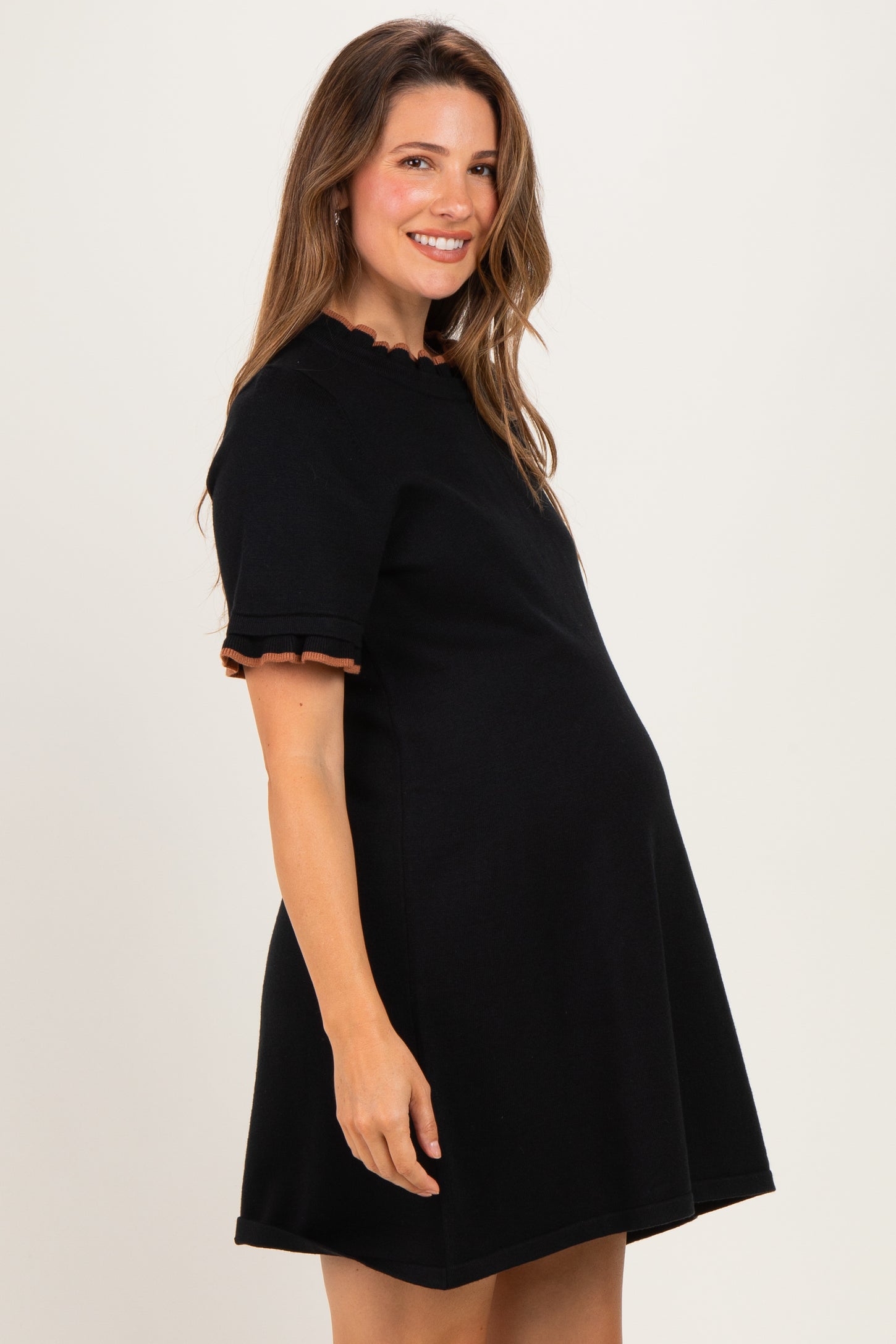 woman wearing a black maternity dress with ruffled short sleeves and a visible baby bump