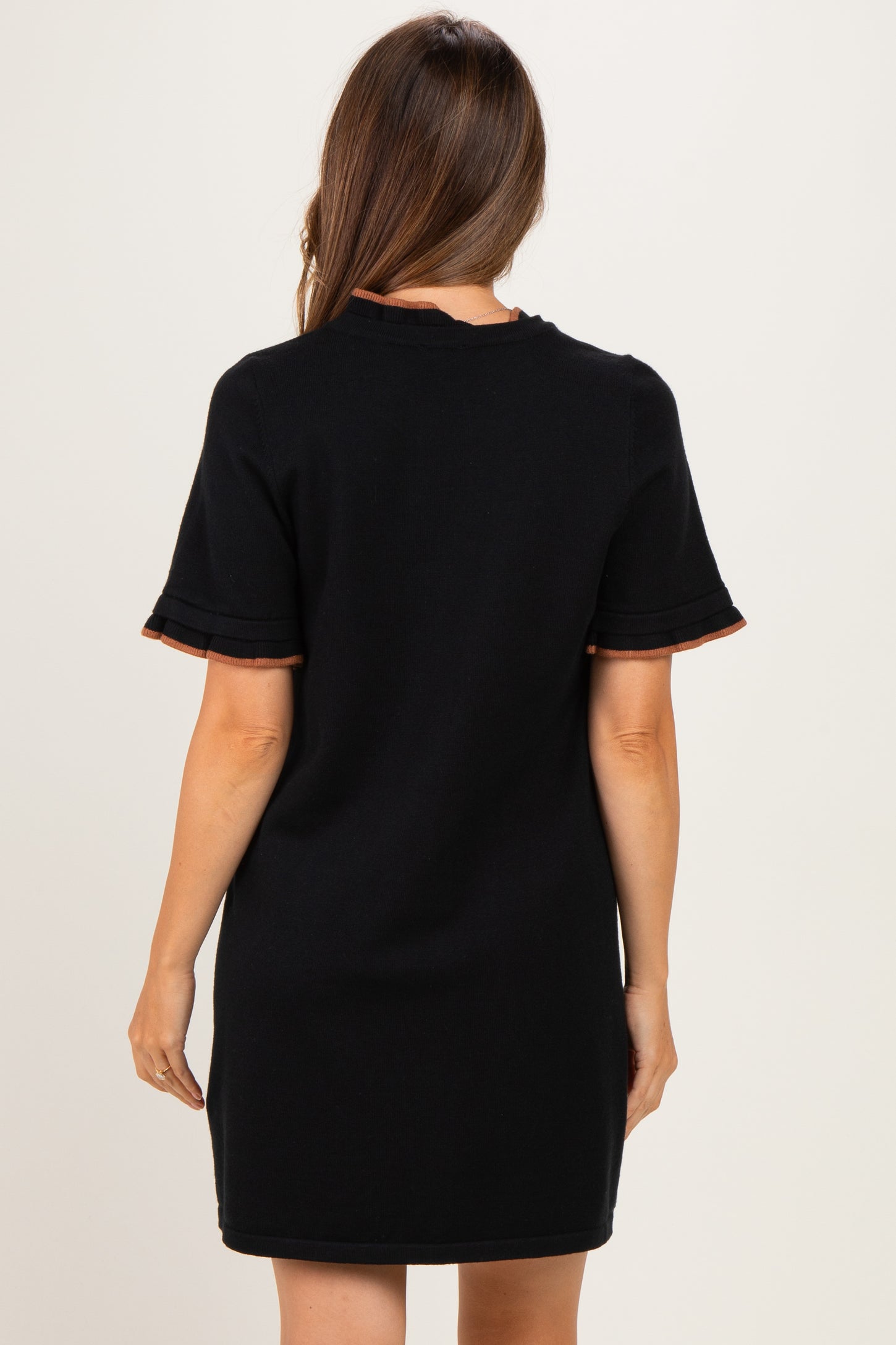 woman wearing a black maternity dress with cuffed sleeves and contrasting trim, viewed from the back
