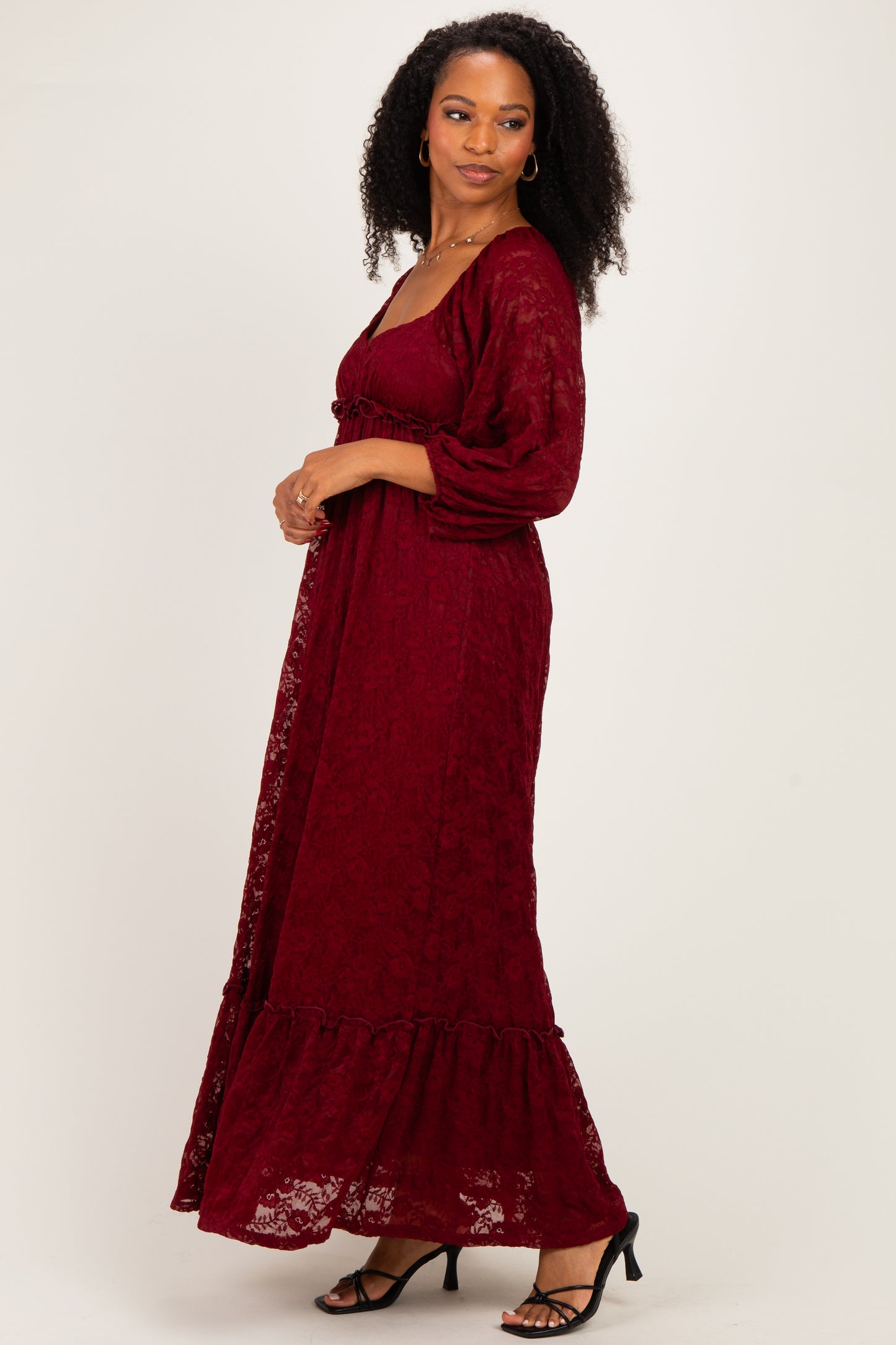 woman wearing a burgundy lace maxi dress with a ruffled hem and puffy sleeves