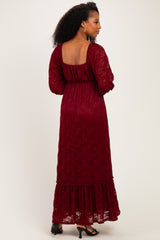 woman wearing a burgundy lace maxi dress with long sleeves and a ruffled hem, viewed from the back
