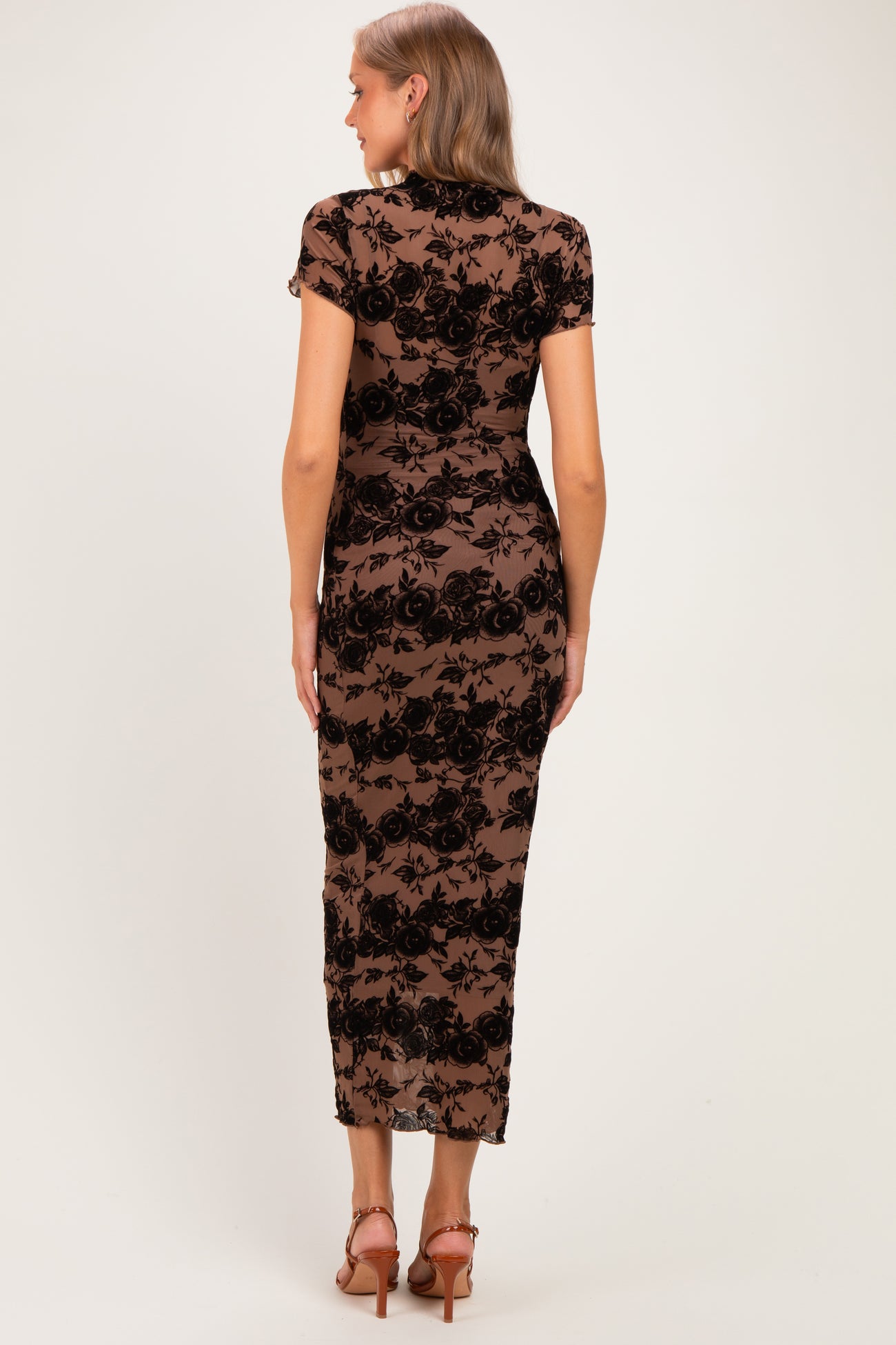woman wearing a black lace maternity dress with short sleeves and a fitted silhouette, showing a smooth silhouette from the back