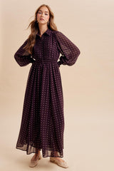 woman wearing a long burgundy polka dot maxi dress with a smocked waist and puff sleeves