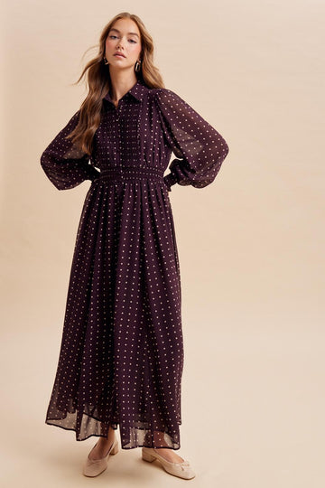 woman wearing a long burgundy polka dot maxi dress with a smocked waist and puff sleeves