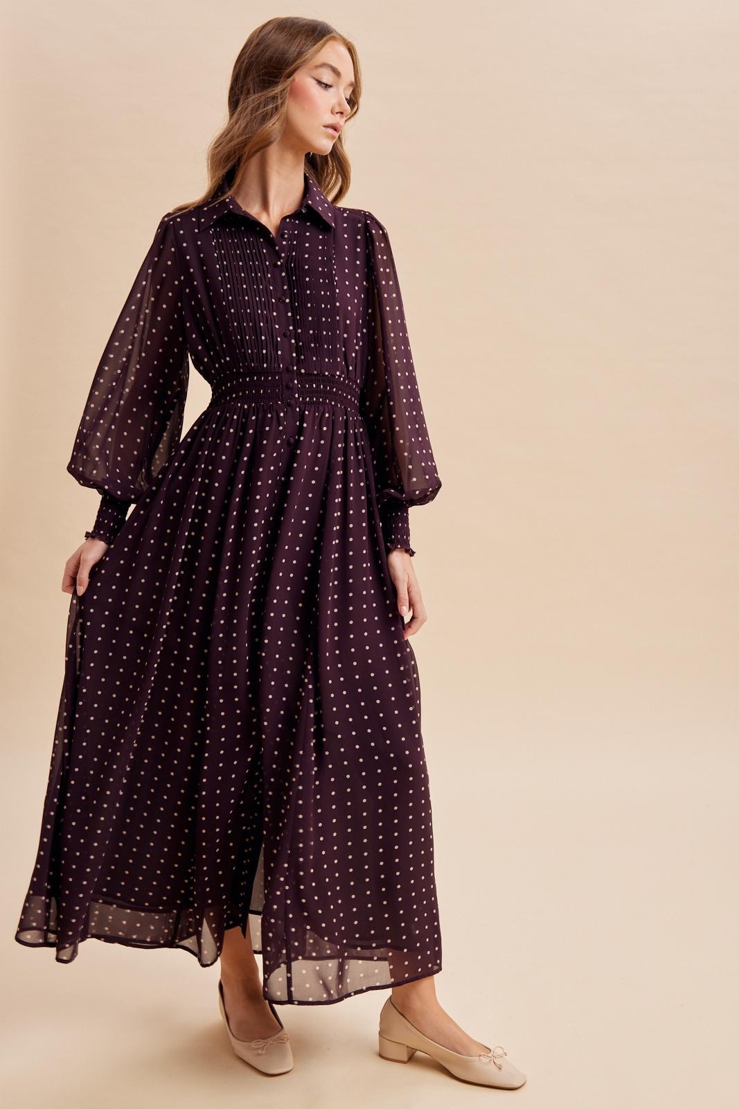 woman wearing a long purple polka dot maxi dress with a button-up collar and puff sleeves