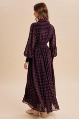 woman wearing a long purple polka dot dress with bell sleeves and a cinched waist, viewed from the back