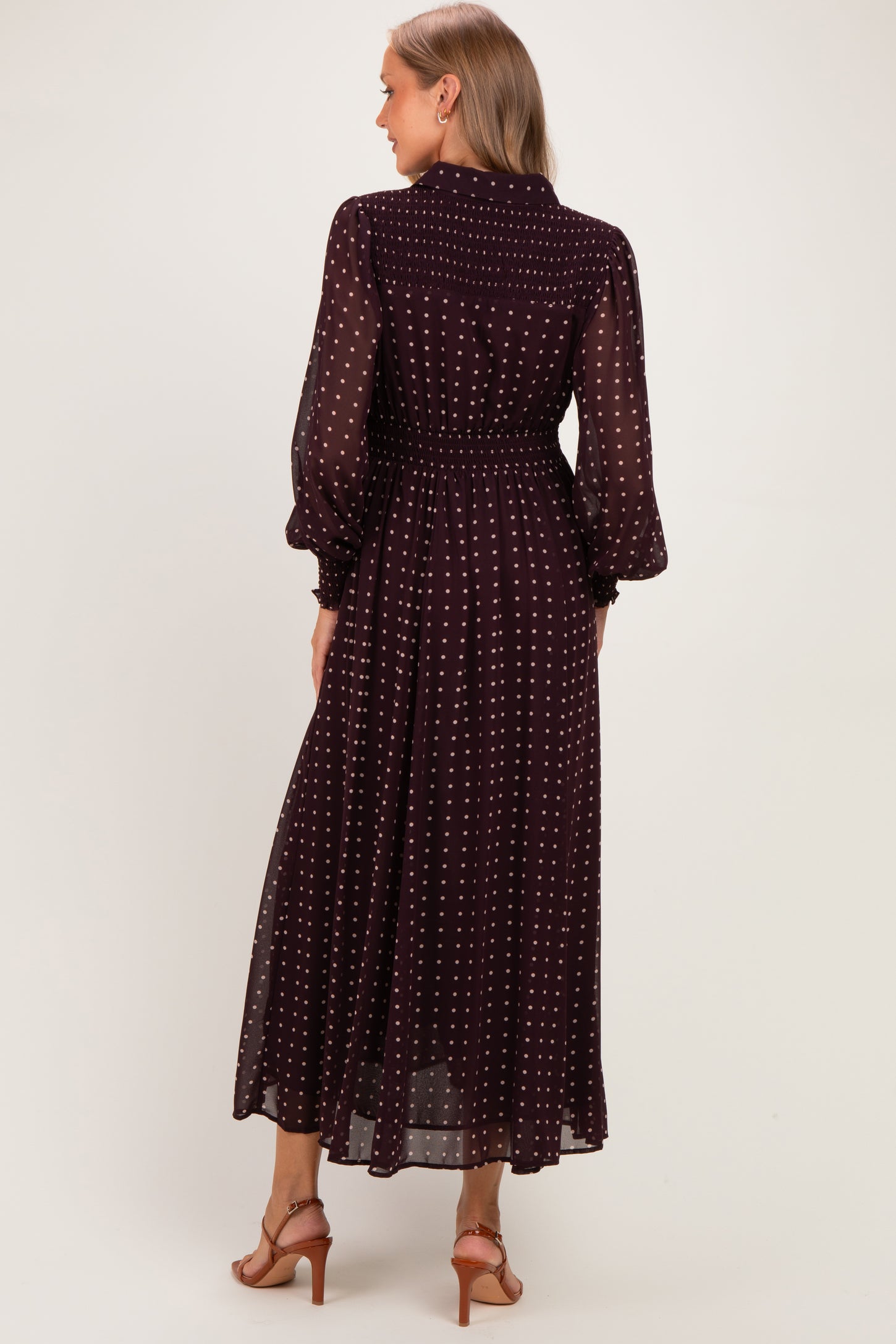woman wearing a burgundy polka dot maternity dress with long sleeves and a cinched waist, seen from the back
