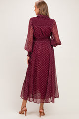 woman wearing a burgundy polka dot maternity dress with long sheer sleeves and a cinched waist, seen from the back