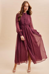 woman wearing a burgundy long sleeve polka dot maxi dress with a tiered skirt and button details