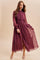 woman wearing a burgundy long sleeve polka dot maxi dress with a tiered skirt and button details