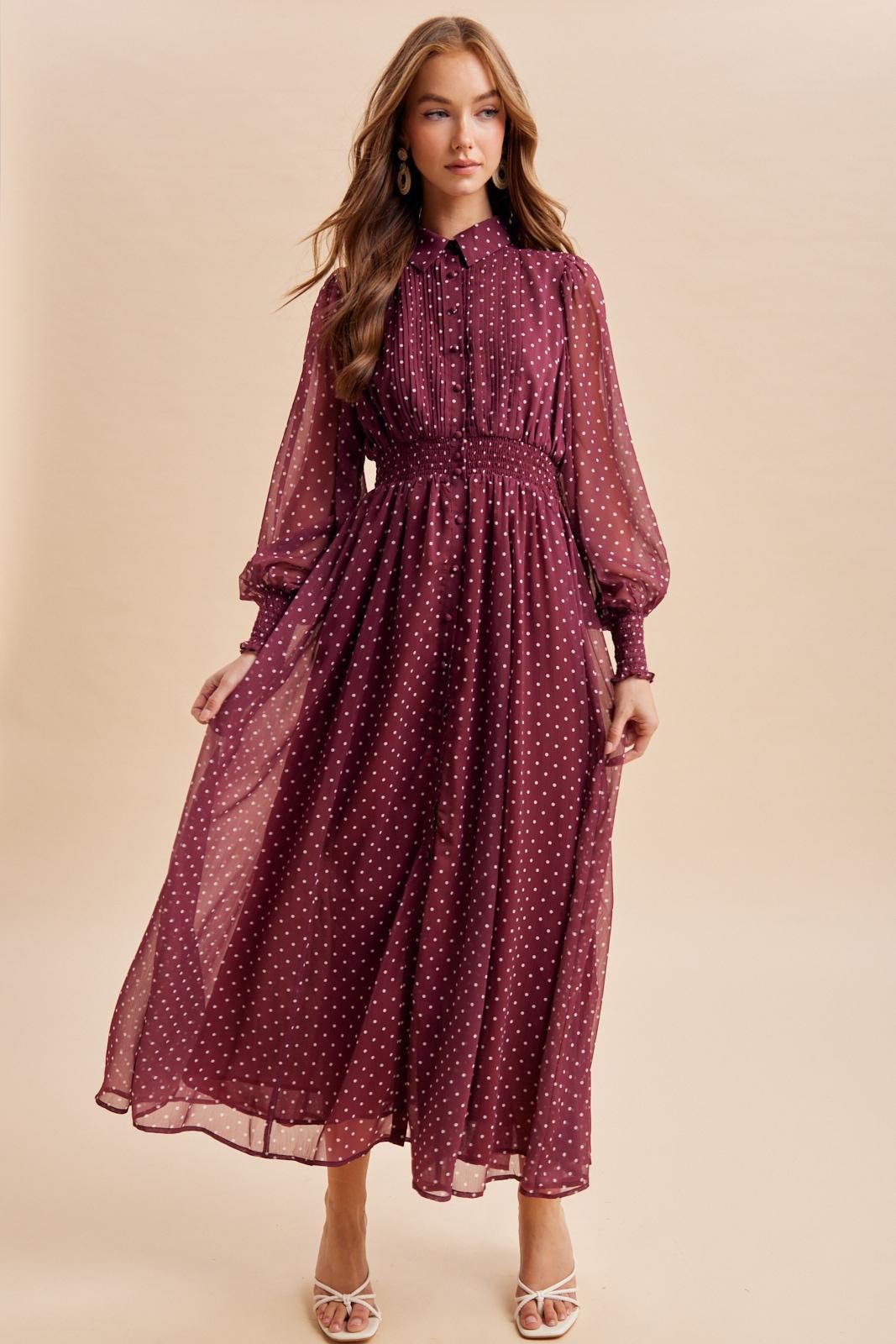 woman wearing a burgundy polka dot maxi dress with a cinched waist and puff sleeves
