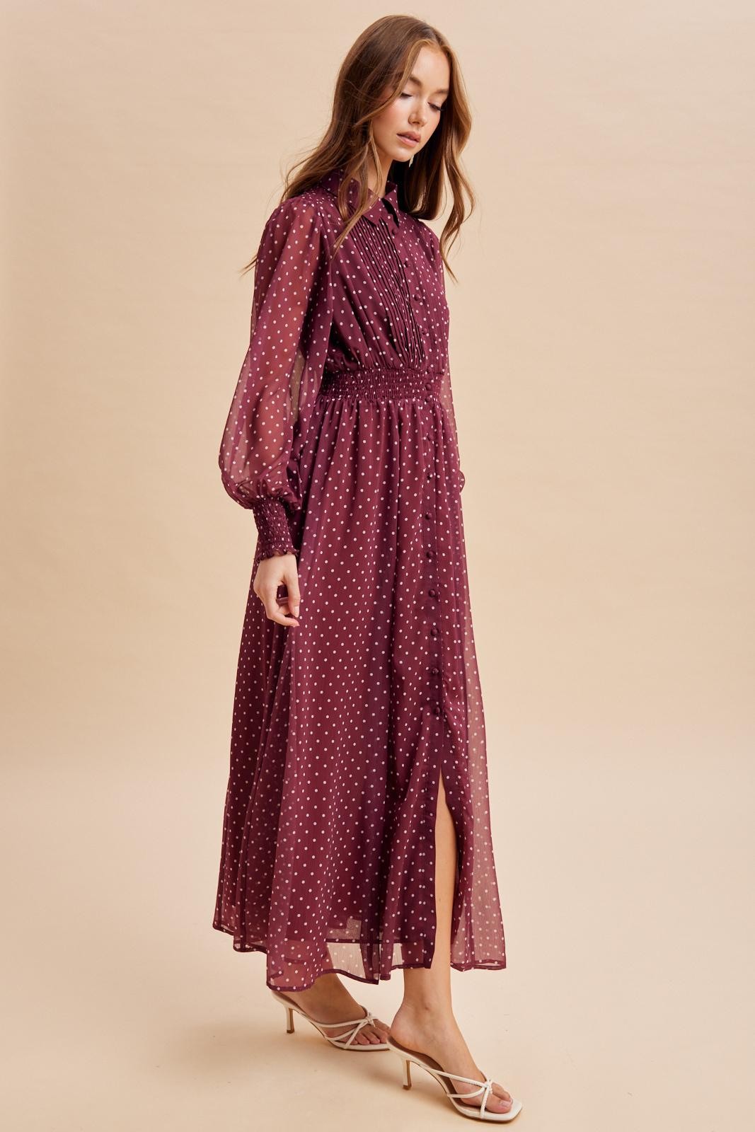 woman wearing a burgundy long sleeve polka dot maxi dress with a cinched waist and front slit