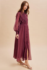 woman wearing a burgundy long sleeve polka dot maxi dress with a cinched waist and front slit