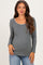 woman wearing a gray long sleeve maternity top with a scoop neckline and decorative trim, showing her baby bump